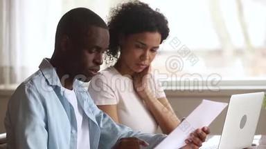 做文书工作的认真的非裔美国人夫妇一起使用笔记本电脑